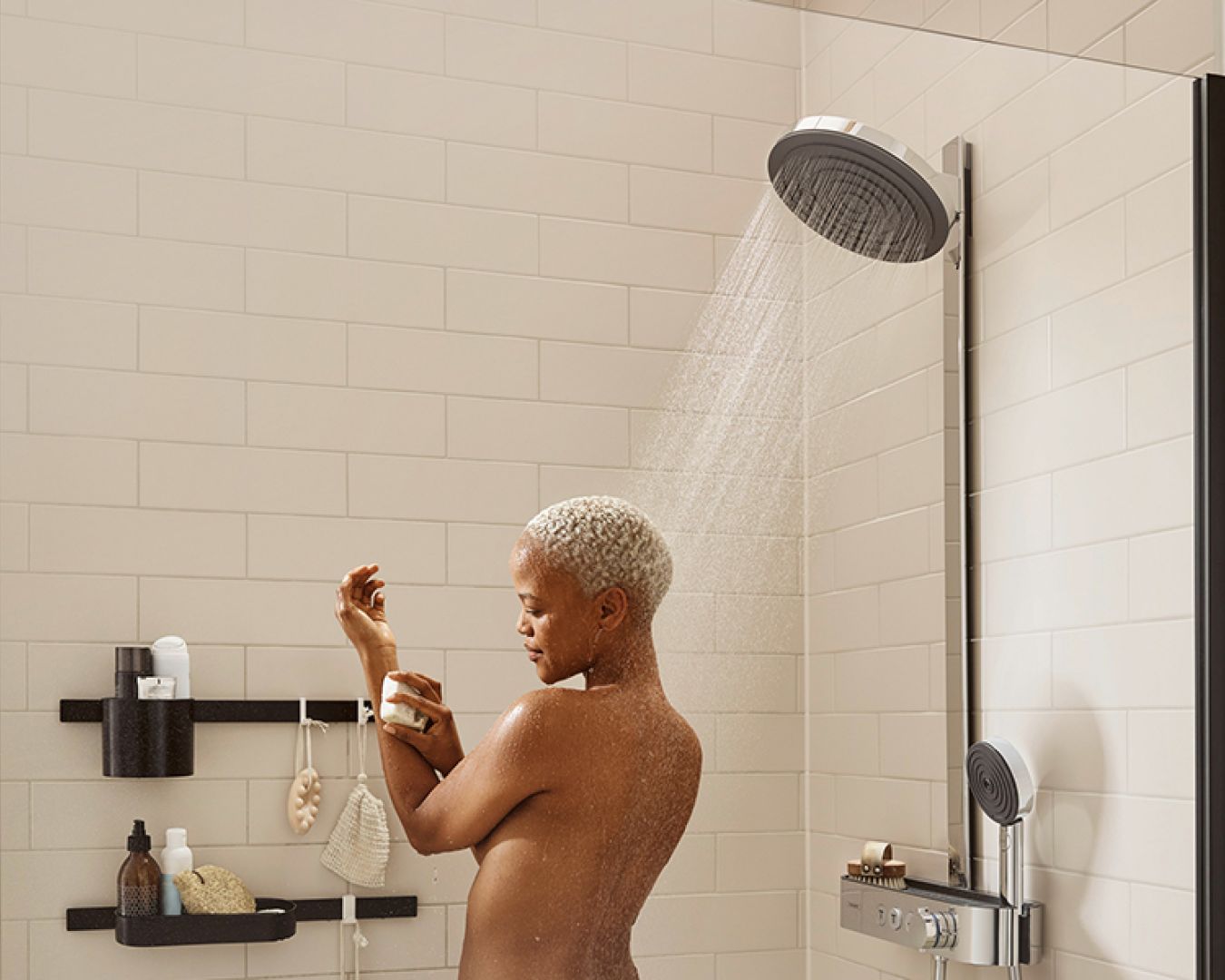 Hansgrohe Person mit kurzem Haar duscht unter moderner Regendusche in heller Fliesendusche.