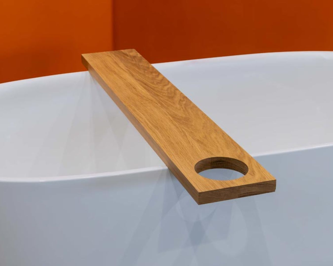 Schlichte Holzablage mit Aussparung auf Badewanne mit orangefarbener Wand

