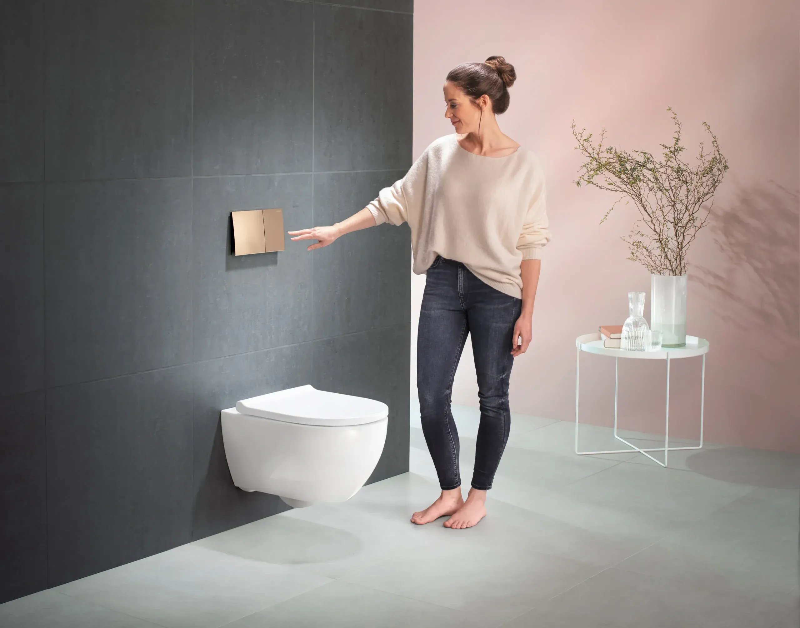 Frau betätigt berührungslose Spültaste an Wand-WC.