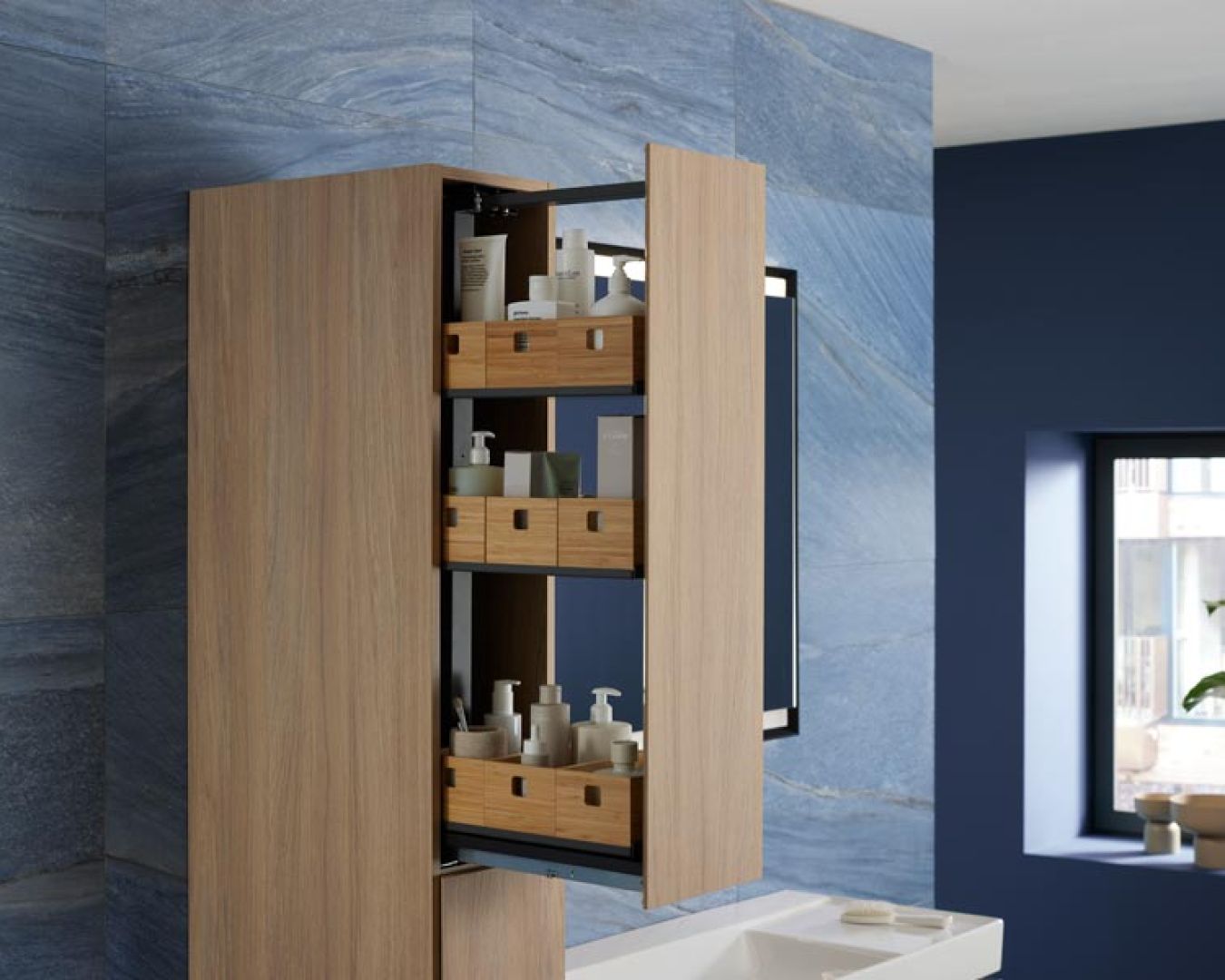 Offener Badhochschrank mit Holz-Auszügen und Pflegeprodukten vor blauer Wand.

