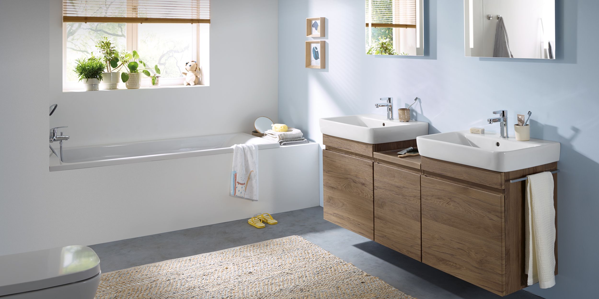 geberit Helles Familienbad mit Doppelwaschtisch, Badewanne und Holzdekor.