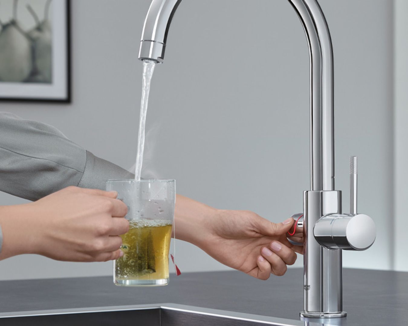 grohe Moderne Armatur füllt heißes Wasser in ein Glas mit Teebeutel.