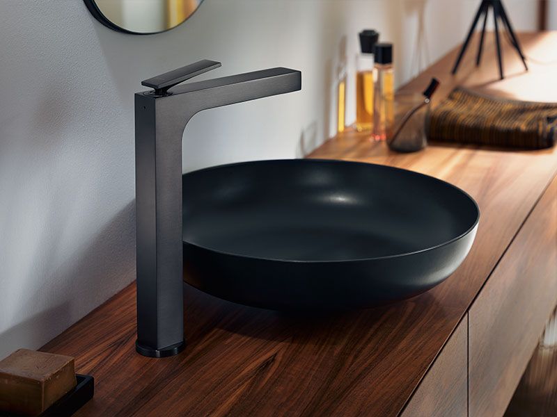 Schwarzer Design-Waschtisch mit matter Armatur auf Holzkonsole.