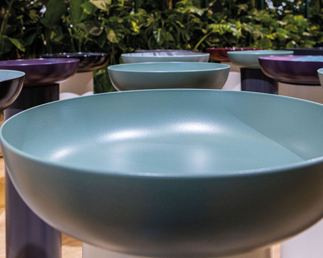 Bunte Aufsatzwaschbecken vor grünem Hintergrund in moderner Ausstellung