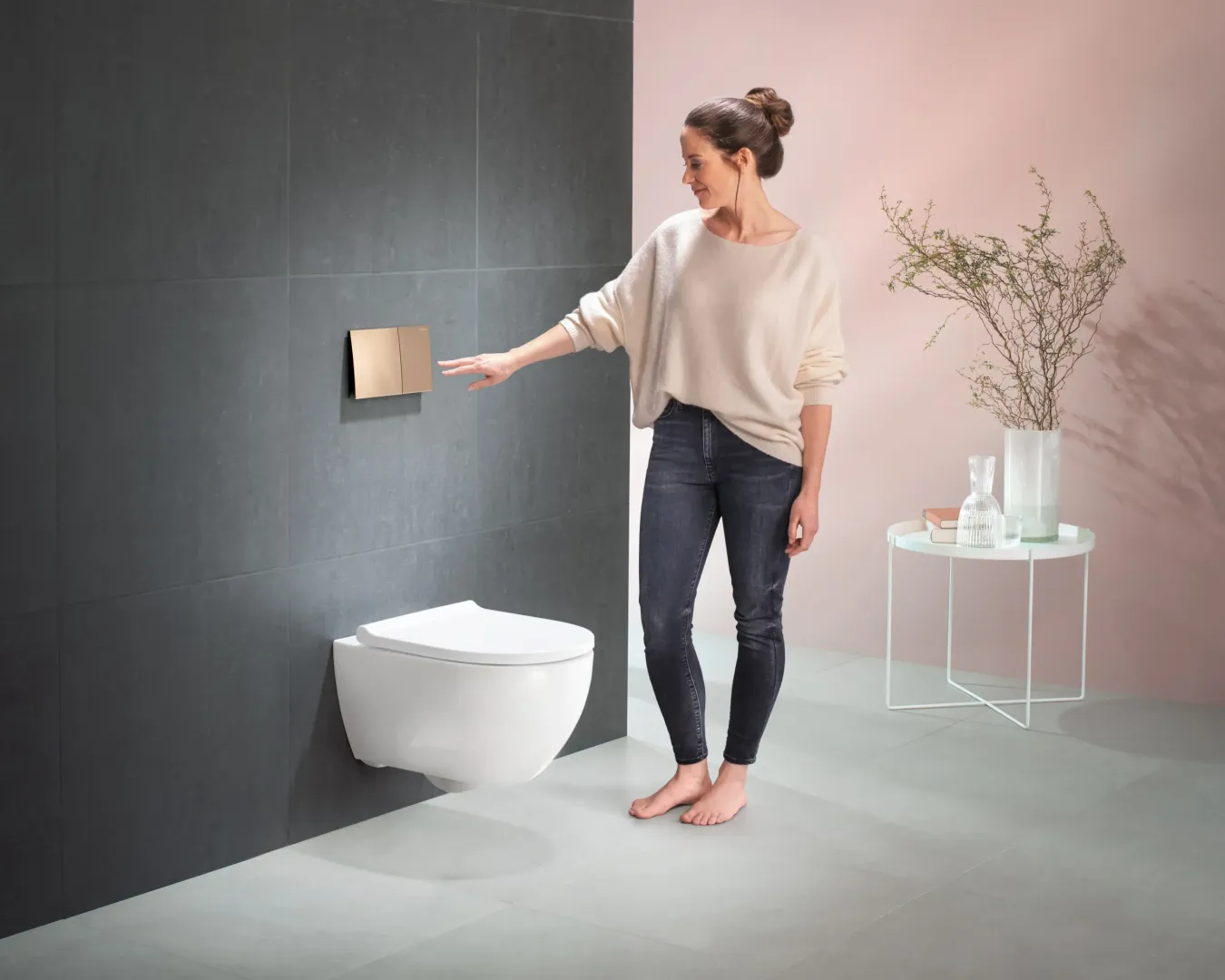 Frau betätigt berührungslose Spültaste an Wand-WC.