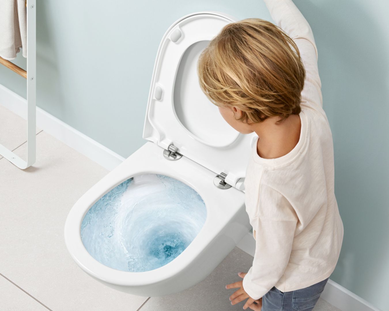 Kind betätigt Spülung an WC mit kraftvollem Wasserwirbel