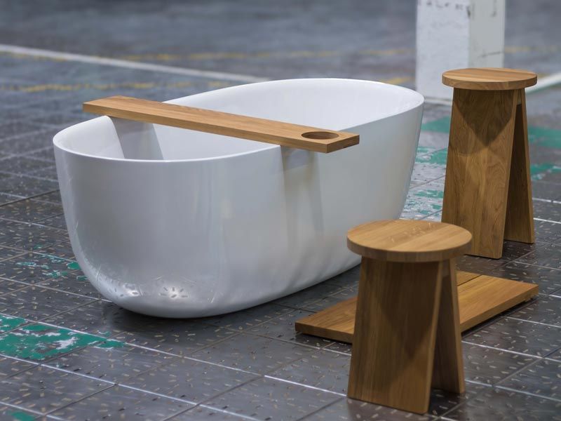 Freistehende Badewanne mit Holzauflage und Hocker auf Industriefliesen