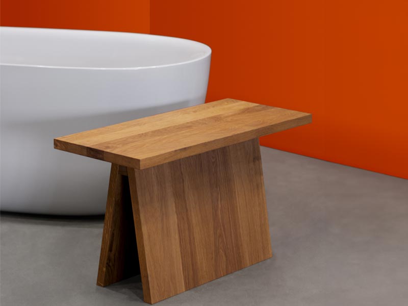 Minimalistische Holzbank vor freistehender Badewanne auf Betonboden

