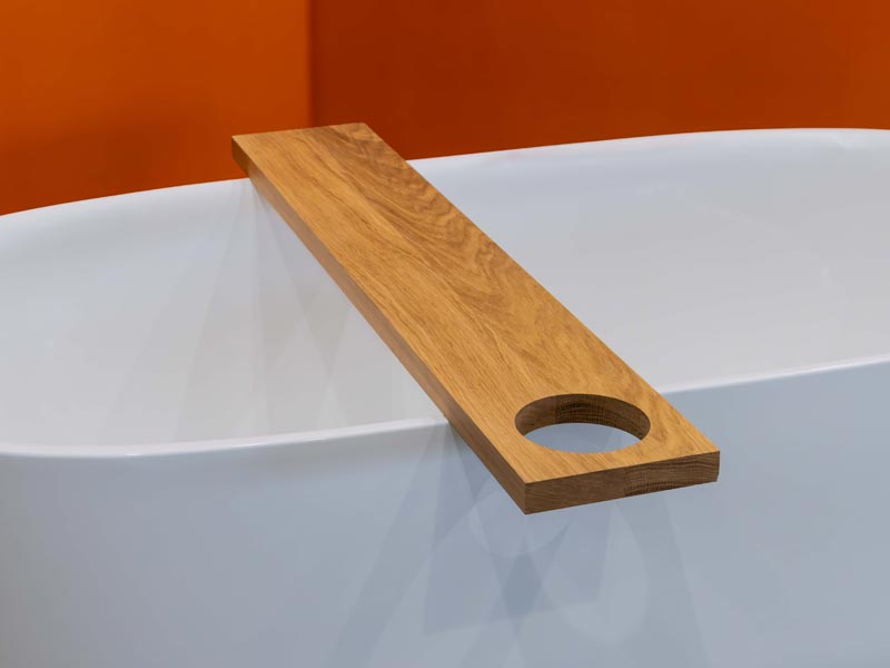 Schlichte Holzablage mit Aussparung auf Badewanne mit orangefarbener Wand

