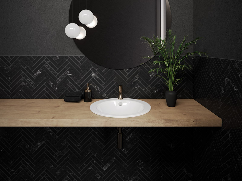 Waschplatz mit schwarzer Wand, Holzplatte und weißem Einbauwaschbecken.