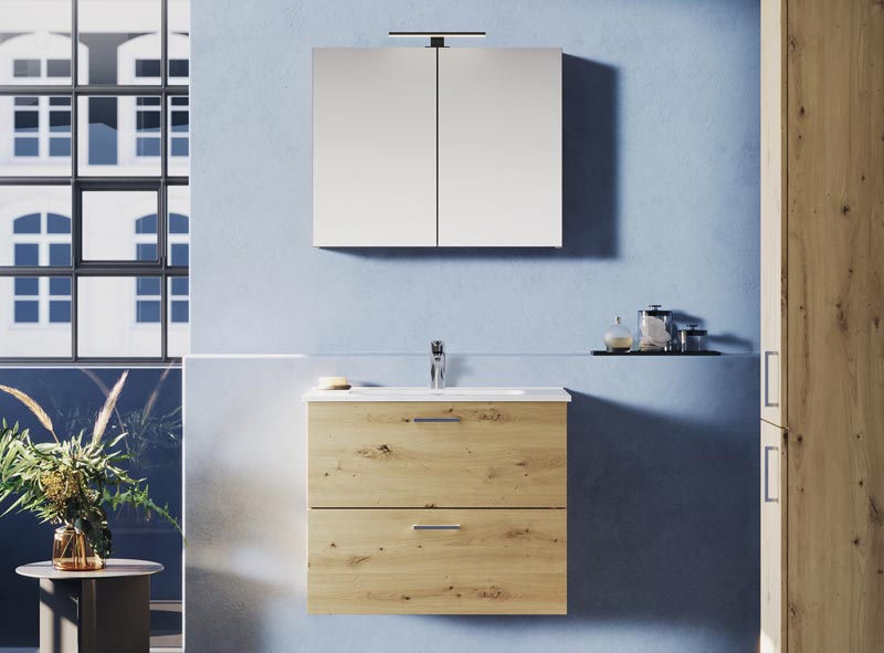 Holz-Waschtisch mit Spiegel und Waschbecken vor blauer Wand im Tageslicht.