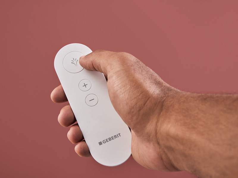 Geberit-Fernbedienung für Dusch-WC mit Sprühfunktion und Plus/Minus-Tasten.

