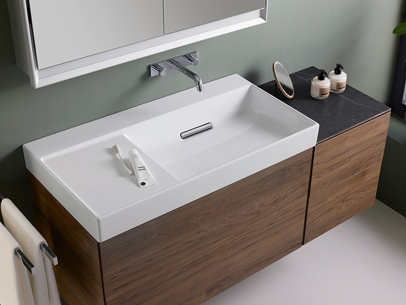 Modernes Waschbecken mit Holzunterschrank, Wandarmatur und Pflegeprodukten.