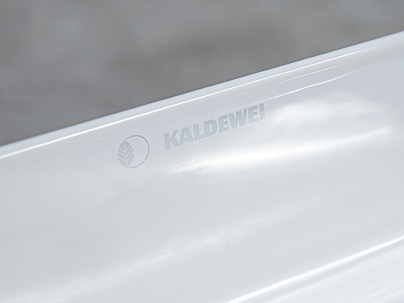 Prägelogo von Kaldewei auf weißer, glänzender  keramik Badoberfläche.