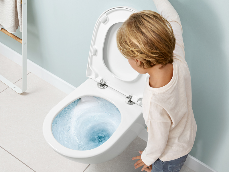 Kind betätigt Spülung an WC mit kraftvollem Wasserwirbel
