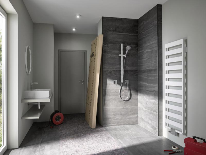 Badezimmer mit Dusche, Handtuchheizkörper und Waschbecken im Rohbauzustand








